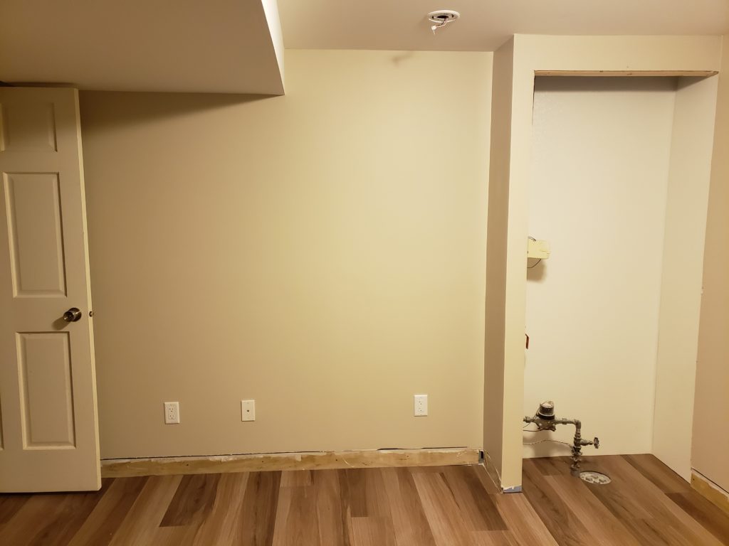 Finished basement wall including a water and sewer service closet.