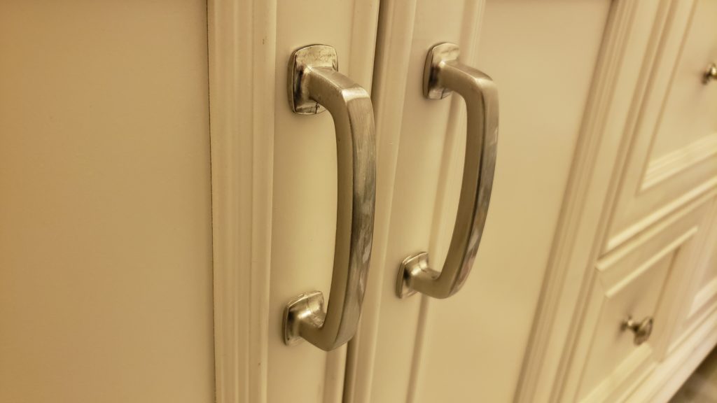 A pair of silver door pull handles on cabinet doors.