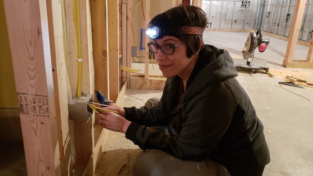 Stripping wires as part of an electrical rough-in project in a basement.