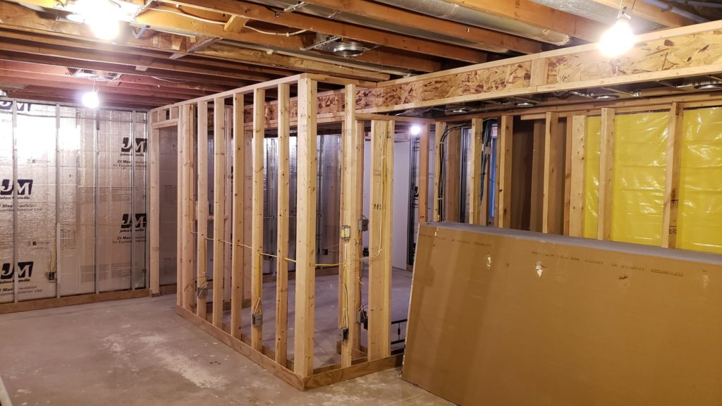 Stacks of drywall sheets leaning against basement wall framing.