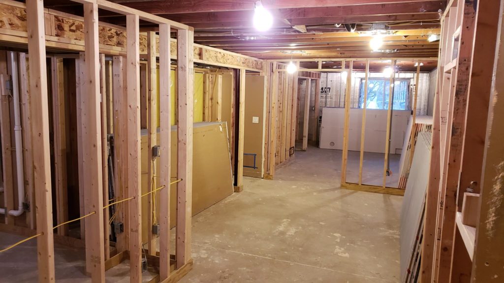 Stacks of drywall sheets leaning against basement wall framing.