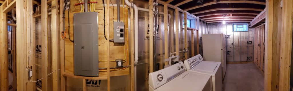 Panoramic view of an unfinished laundry room with stud walls.