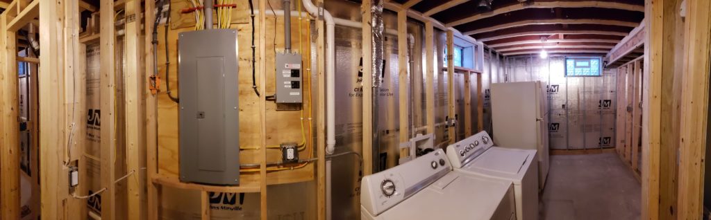 Panoramic view of an unfinished laundry room with stud walls.