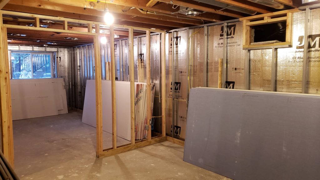 Stacks of drywall sheets leaning against basement wall framing.