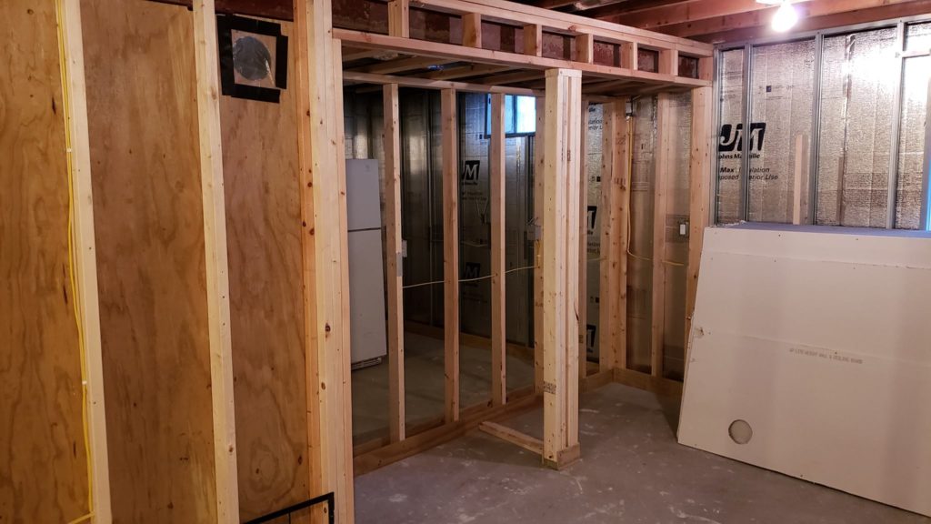 Stud wall framing for a pair of closets in a basement.