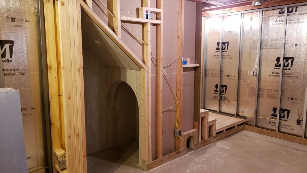 Archway under basement stairs covered with decorative paneling.