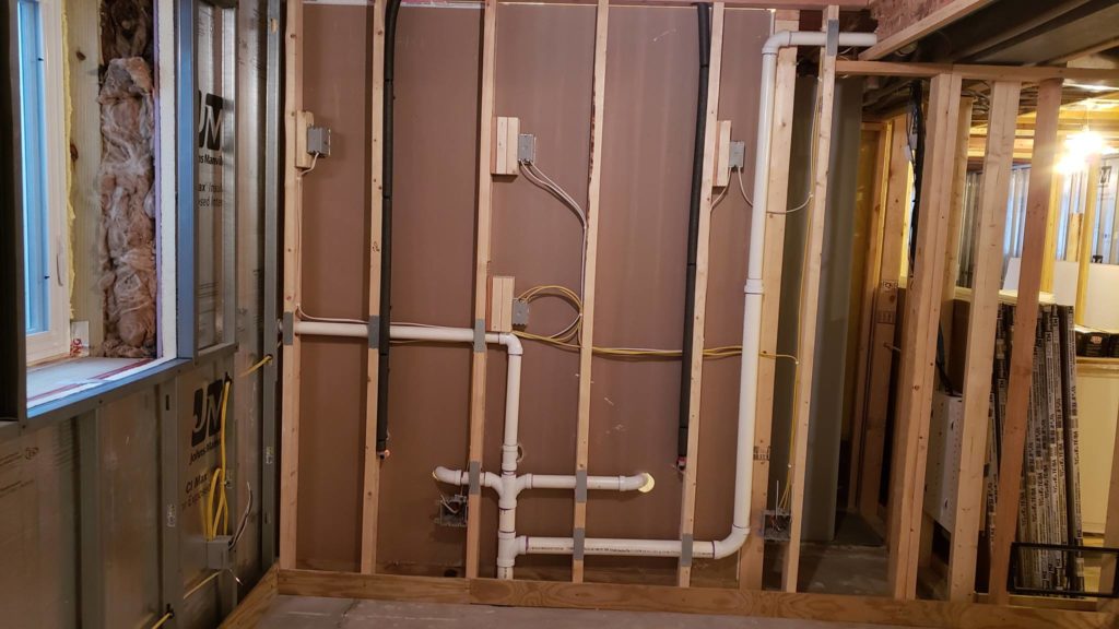 Plumbing and wiring in a stud wall for a bathroom vanity as seen from the back side of the wall.